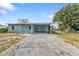 Single story home featuring a wide driveway, mature landscaping, and a covered carport entryway at 103 Curtis Ne Ter, Port Charlotte, FL 33952