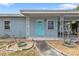 Home exterior showcasing a covered porch with decorative columns, a blue door, and gravel landscaping at 103 Curtis Ne Ter, Port Charlotte, FL 33952