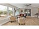 Sunlit living room with wood-look flooring, comfortable seating, and large windows overlooking the yard at 103 Curtis Ne Ter, Port Charlotte, FL 33952