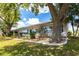 Single story home with lush landscaping, healthy grass and a large mature shade tree in the backyard at 1872 Birmingham Blvd, Port Charlotte, FL 33980