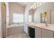 A soothing bathroom offers a large soaking tub, double vanity, and soft floral wallpaper at 1872 Birmingham Blvd, Port Charlotte, FL 33980