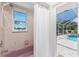 Well-lit bathroom featuring a bathtub, shower with white shower curtain, and window overlooking pool at 2244 Meetze St, Port Charlotte, FL 33953