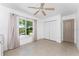 Neutral bedroom with tile flooring, ceiling fan, closet, and serene backyard views through the window at 2244 Meetze St, Port Charlotte, FL 33953
