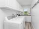 Functional laundry room with white washer and dryer, storage cabinets, and wood-look flooring at 2244 Meetze St, Port Charlotte, FL 33953