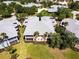 Aerial view of a yellow residential condo with a grey roof surrounded by trees and neighboring units at 25559 Heritage Lake Blvd # 25, Punta Gorda, FL 33983
