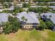 Aerial view of a yellow condo building featuring a grey roof, tropical landscaping, and screened-in lanais at 25559 Heritage Lake Blvd # 25, Punta Gorda, FL 33983