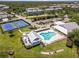 Aerial shot of community pool and amenities area, including a pool house, tennis courts, and parking at 25559 Heritage Lake Blvd # 25, Punta Gorda, FL 33983