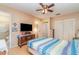 This bedroom features a ceiling fan, a TV on a bureau, and an adjacent bathroom at 402 Cicero Nw St, Port Charlotte, FL 33948