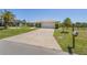 Charming single-story home featuring a well-manicured lawn, mature palm trees, and a long driveway leading to an attached garage at 4146 Library St, Port Charlotte, FL 33948