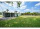 A large backyard with lawn and a screened in porch along the back of the house at 654 Aqui Esta Dr, Punta Gorda, FL 33950