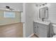 Bathroom with vanity, toilet, and doorway to bedroom area with wood look tile flooring at 654 Aqui Esta Dr, Punta Gorda, FL 33950