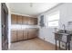 Bright laundry room featuring a utility sink, wood cabinets and tile flooring at 661 Athos Ter, Port Charlotte, FL 33952