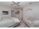 This bedroom features gray-washed wood floors, neutral walls, a ceiling fan, a bed, and a sitting chair at 8117 Thruso Rd, Port Charlotte, FL 33981
