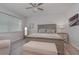 This bedroom features a ceiling fan, gray-washed wood floors, neutral walls, a bed, and a sitting bench at 8117 Thruso Rd, Port Charlotte, FL 33981