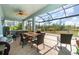 Enclosed patio with a hot tub, ceiling fan, and outdoor seating area with a table, grill, and view of the backyard at 8117 Thruso Rd, Port Charlotte, FL 33981