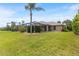 The spacious backyard features lush green grass, mature landscaping, and an inviting screened-in lanai at 1240 Alpinia Rd, North Port, FL 34288
