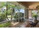 Cozy screened-in porch featuring tile flooring, a bench, and serene views of the landscaped front yard at 1240 Alpinia Rd, North Port, FL 34288