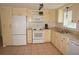 Bright kitchen features white appliances, neutral cabinets, and a window for natural light at 1270 Manor Rd, Englewood, FL 34223
