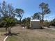 Backyard with a small storage shed amid mature trees and tropical landscaping at 1270 Manor Rd, Englewood, FL 34223