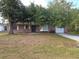 Charming single-story brick home with a well-maintained lawn and mature trees providing shade at 18054 Ackerman Ave, Port Charlotte, FL 33948