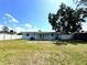 Expansive backyard showcasing a well-maintained lawn, a patio, a white fence, and lush trees at 2600 Mohegan Rd, Venice, FL 34293
