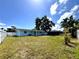 Large backyard view with a blue house, a patio, a white fence, and lush trees at 2600 Mohegan Rd, Venice, FL 34293