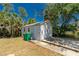Side view of a detached one car garage with a concrete driveway amid lush greenery under a clear blue sky at 2690 Auburn Blvd, Port Charlotte, FL 33948