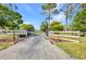 Gated driveway entrance featuring a white fence and black iron gate and the property address on a sunny day at 29324 Leah Rd, Punta Gorda, FL 33982