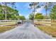 Gated driveway entrance featuring a white fence and black iron gate and the property address on a sunny day at 29324 Leah Rd, Punta Gorda, FL 33982