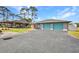 Spacious garage with teal doors and adjacent carport, providing ample parking and storage space for vehicles and equipment at 29324 Leah Rd, Punta Gorda, FL 33982