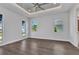 Spacious bedroom with tray ceilings, ceiling fan, and wood-look tile flooring illuminated by three windows at 3712 Carmichael Dr, Punta Gorda, FL 33950