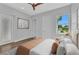 Neutral bedroom showcasing hardwood flooring, white doors, a ceiling fan, and bright views from the window at 3712 Carmichael Dr, Punta Gorda, FL 33950