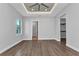 Open bedroom with tray ceiling, ceiling fan, and wood-look tile flooring, adjacent to closet and bathroom at 3712 Carmichael Dr, Punta Gorda, FL 33950