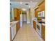 Bright kitchen with wooden cabinetry, white appliances, and neutral tile flooring at 3721 Adelaide Ave, North Port, FL 34288