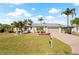 Inviting home featuring a well-kept lawn, mature palm trees, and a brick driveway at 441 Norma Ct, Punta Gorda, FL 33950