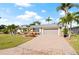 Charming home offers a manicured lawn, mature palm trees, and inviting brick driveway at 441 Norma Ct, Punta Gorda, FL 33950