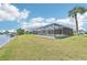 Backyard view of the screened pool with waterfront access and a lush lawn at 5194 Cooper Ter, Port Charlotte, FL 33981