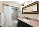 Bright bathroom features a granite countertop, a decorative mirror, and a shower with a tiled surround at 5194 Cooper Ter, Port Charlotte, FL 33981