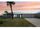 Charming single-story home with manicured lawn, mature palm trees, and a two-car garage at sunset at 5194 Cooper Ter, Port Charlotte, FL 33981
