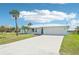Inviting single-story home featuring a well-manicured lawn, beautiful palm trees, and a clean white driveway at 5194 Cooper Ter, Port Charlotte, FL 33981