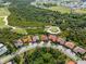 This aerial showcases golf community homes with tile roofs, situated near a lush golf course and wooded areas at 5428 Royal Poinciana Way, North Port, FL 34291