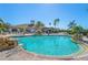 Sparkling community pool with rock waterfall feature, surrounded by palm trees and lounge chairs at 5428 Royal Poinciana Way, North Port, FL 34291