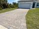 Paver driveway leading to a two-car garage on a home with manicured lawn and landscaping at 7474 Manville Ter, Port Charlotte, FL 33981