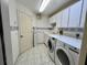 Bright laundry room featuring tile flooring, front-load machines, white cabinets, and a floral accent border at 1305 Alton Rd, Port Charlotte, FL 33952