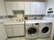 Well-lit laundry area with white cabinetry, tile floors, sink, and modern front-load washer and dryer units at 1305 Alton Rd, Port Charlotte, FL 33952