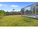 Spacious backyard with a screened-in pool, lush lawn, and a privacy fence at 13235 Essman Ave, Port Charlotte, FL 33953