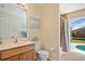 Bathroom features a vanity, toilet, shower, and a view of the pool and backyard area at 13235 Essman Ave, Port Charlotte, FL 33953