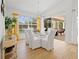Bright dining room with light wood floors, glass table, white chairs, yellow accents and view to screened-in porch at 13235 Essman Ave, Port Charlotte, FL 33953