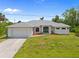 Charming single-story home with a well-manicured lawn, attached garage, and a welcoming blue front door at 13235 Essman Ave, Port Charlotte, FL 33953