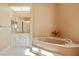 Well-lit bathroom features a corner tub, white tiled floors, and white cabinets at 149 Albert Ln, Port Charlotte, FL 33954